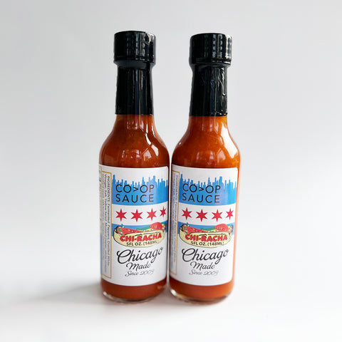 Two bottles of Co>Op Hotsauce Chiracha placed against a white background.